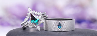Two silver rings with gemstones on a dark stone surface with a blurred purple background
