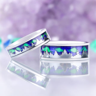 Aurora Borealis Forest couples ring set, two tungsten bands with blue and green northern lights inlay and silver tree silhouettes, shown as a pair