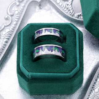 Aurora Borealis northern lights and trees matching wedding bands presented together in a green velvet ring box