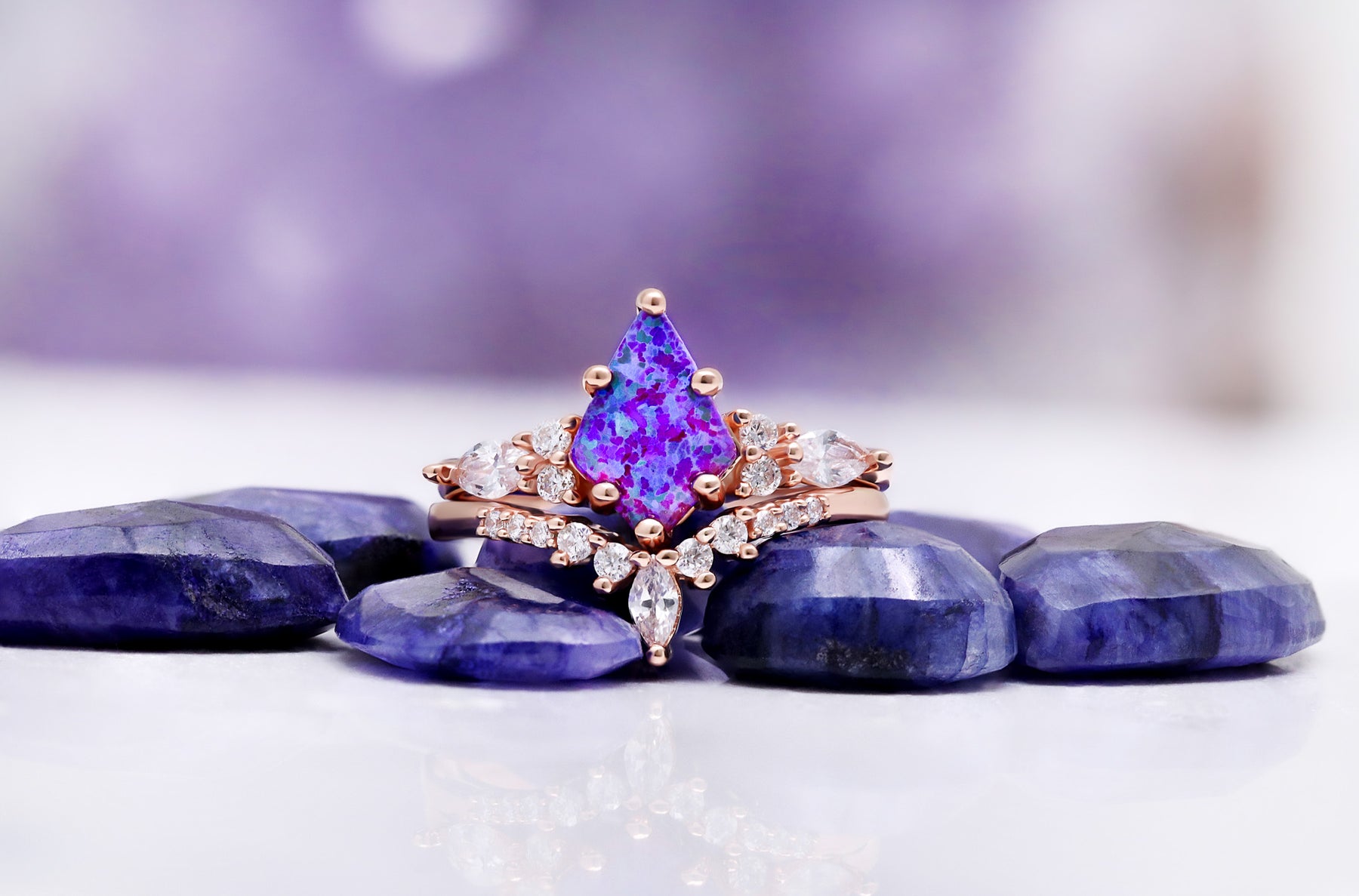 Skye Kite Purple Fire Opal ring set by Aquamarise shown in a lavender banner composition