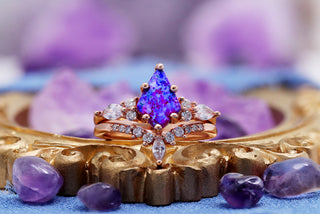 Skye Kite Purple Fire Opal ring set by Aquamarise shown in a lavender banner composition, alternate crop