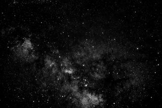 Black and white image of a starry night sky with a nebula.