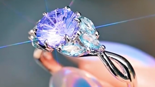 Lavender sapphire ring held by a hand with a blurred background