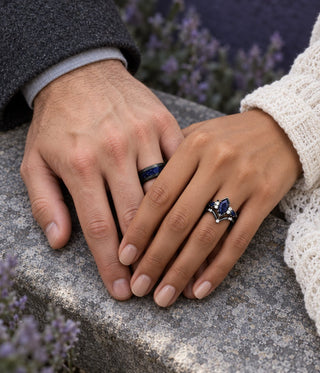 Couple's hands on a stone ledge beside lavender, his black band with blue sandstone inlay and her kite-cut blue sandstone engagement ring, Aquamarise banner