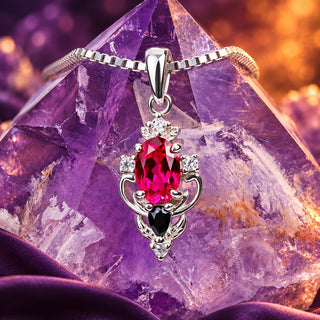 Carmilla lab-grown ruby and black onyx pendant necklace in sterling silver draped over an amethyst crystal point