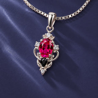 Carmilla lab-grown ruby and black onyx pendant necklace in sterling silver on a box chain over navy satin