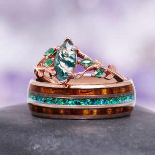 moss agate engagement ring and whiskey barrel wood wedding band set on gray surface over 
purple background