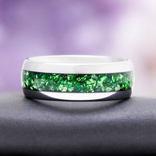 8mm crushed emerald men's wedding band in silver tungsten carbide resting on a dark stone, showing the domed profile and green inlay