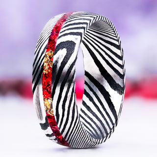 Crushed Red Garnet & Gold Leaf men's wedding band in domed Damascus steel, 8mm, standing upright with the red garnet and gold leaf channel running through the black-and-silver Damascus pattern
