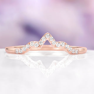 Rose gold ring with diamond accents on a white surface with a blurred purple background