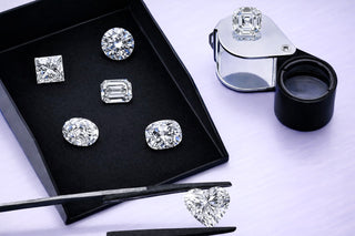Diamond earrings on a black display box with a magnifying glass on a white background