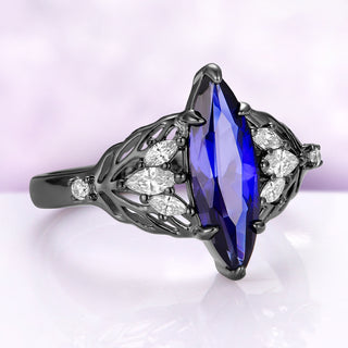 Angled view of the Eilwen sapphire ring in black ruthenium, showing the marquise leaves on each shoulder and the small round stones on the split shank