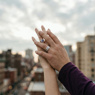 Two hands with rings against a cityscape background