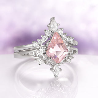 Silver ring with a pink gemstone on a reflective surface with a blurred purple background