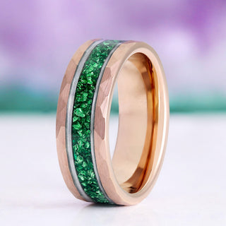 Rose gold ring with green gemstones on a blurred background