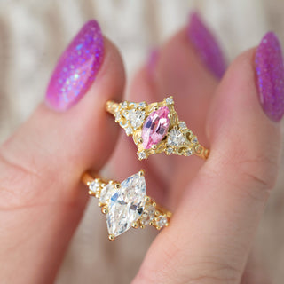 Gold rings with pink and clear gemstones on a hand with purple nail polish.