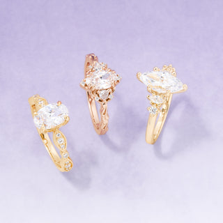 Gold earrings with clear gemstones on a light purple background