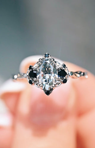 Close-up of a diamond ring held between fingers with a blurred background
