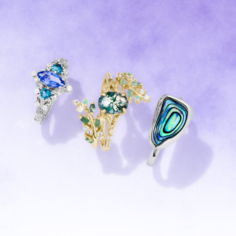 Three decorative rings with gemstones on a light purple background