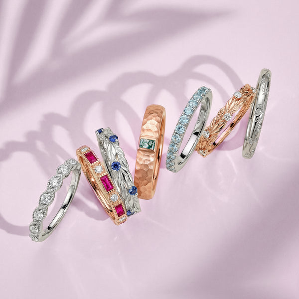 Set of gold and silver rings with gemstones on a pink background