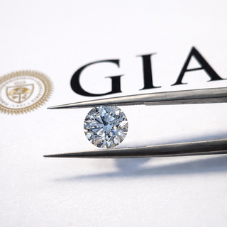 Diamond held by tweezers with GIA logo in the background