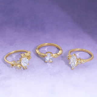 Three gold rings with heart-shaped gemstones on a purple background