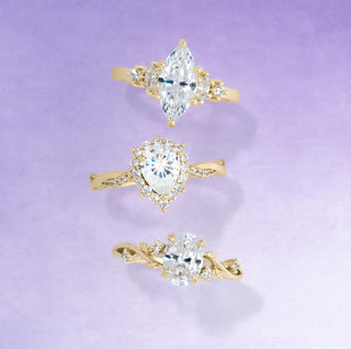 Three gold rings with heart-shaped gemstones on a light purple background