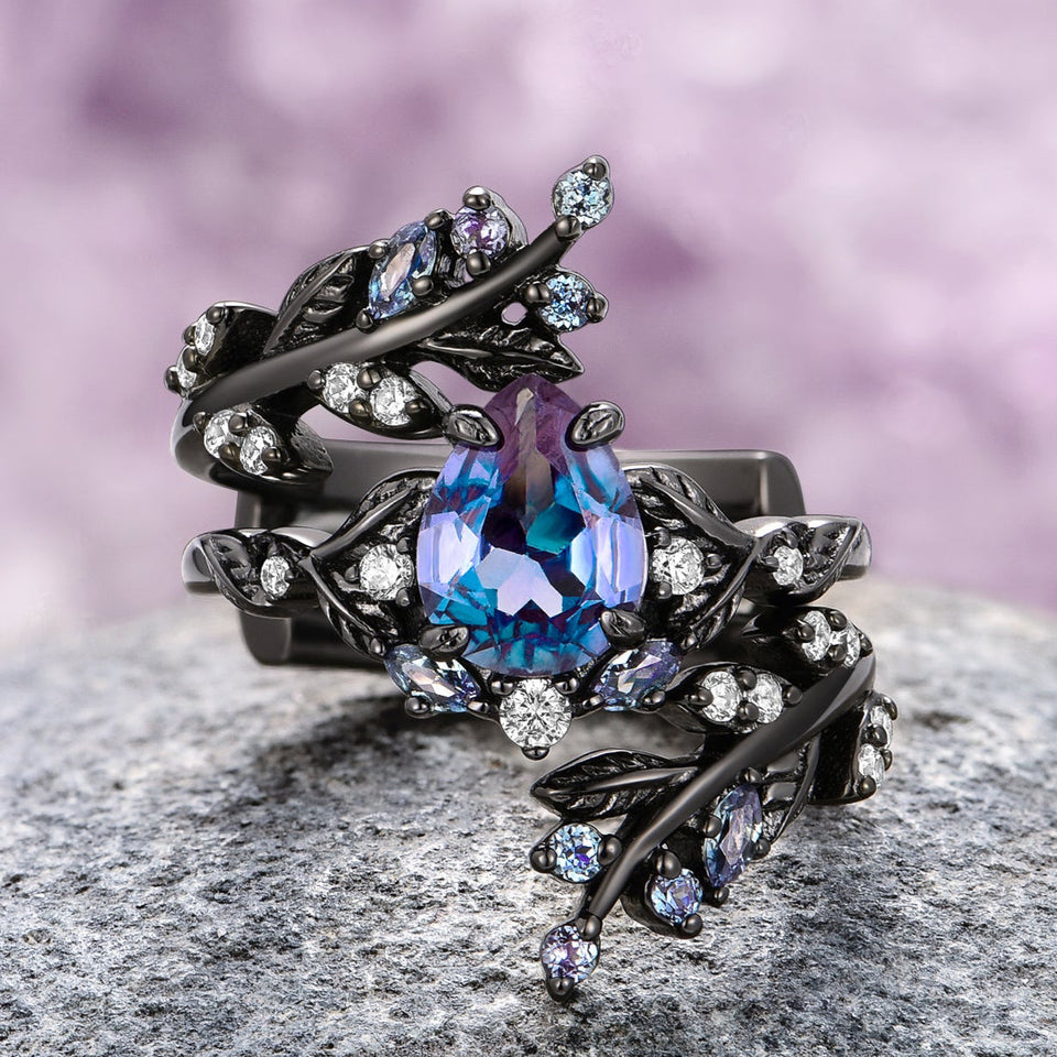 Ornate gothic alexandrite leaf engagement ring set by Aquamarise on a textured surface with a purple background