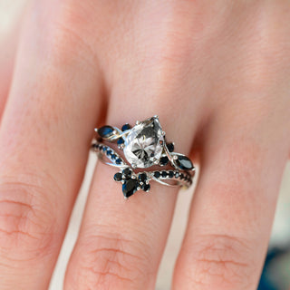 Silver ring with a large diamond and smaller stones on a finger