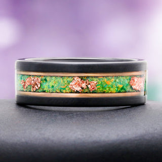 8mm Green Fire Opal and rose gold leaf men's wedding band resting on a dark stone, showing the green opal inlay and rose gold leaf flakes