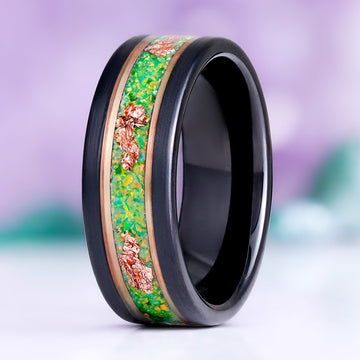 Green Fire Opal and rose gold leaf men's wedding band standing upright, black tungsten with a green opal inlay flecked with rose gold leaf