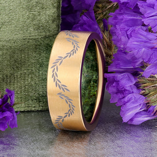 Brushed gold titanium men's band with engraved leaf vine and green moss agate lining the inside, styled with purple flowers