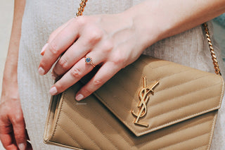 Vintage Alexandrite Ring in 14K Rose Gold Vermeil by Aquamarise, featuring a color-changing alexandrite stone set in a delicate rose gold band, styled on a hand holding a tan purse.