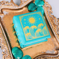 Summer Court Handmade Leather Book Ring Box- Ocean Tide Teal Edition (Small) by Aquamarise, teal leather with gold sun and wave design, on ornate gold tray with teal stones.