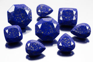 Blue gemstones with gold flecks on a white background by Aquamarise