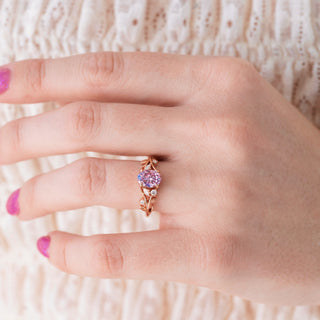 Hand wearing a pink gemstone ring with a white lace background