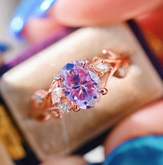 Rose gold ring with a large purple gemstone held in hand