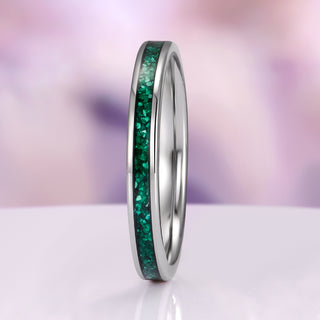 Silver ring with green gemstones on a white and purple gradient background