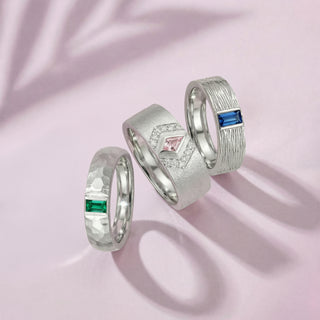 Three silver rings with gemstones on a pink background