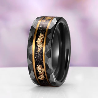 Black ring with gold inlay on a white surface with a purple gradient background