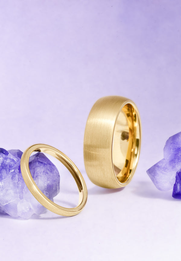 Two gold rings on a light purple background with amethyst stones.