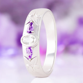 Moissanite & Amethyst wedding band in sterling silver, 6mm, standing upright with the bezel-set oval moissanite flanked by pear amethysts and engraved scrollwork