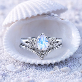 Sterling silver moonstone bridal set with Celtic trinity knot detailing displayed inside a seashell on white sand, Aquamarise collection banner