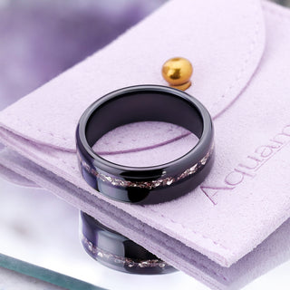 Polished black tungsten men's band with off-set crushed morganite inlay resting on the Aquamarise suede jewelry pouch
