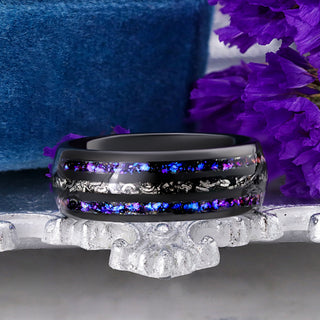 Black tungsten men's band with a center meteorite inlay between two Orion Nebula fire opal channels, displayed on a silver tray