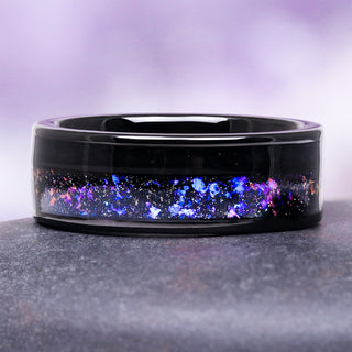Orion Nebula galaxy tungsten wedding band on gray surface over purple background