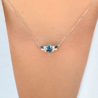 Model wearing the oval blue moissanite cluster necklace in sterling silver at the collarbone