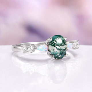 Silver ring with a green gemstone on a white surface with a blurred background