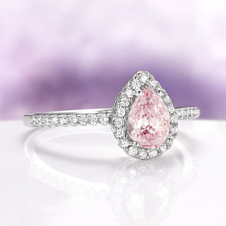 Pink diamond ring with a white gold band on a light purple background