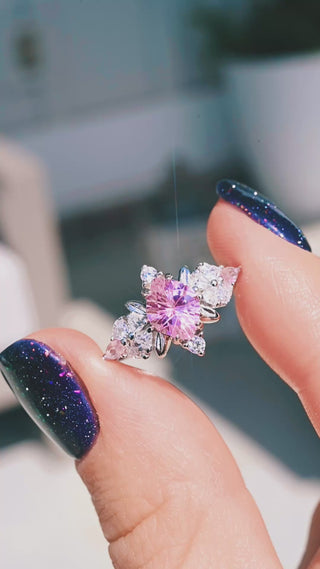 Video of the Noraleaf Lab-Grown Pink Sapphire Engagement Ring in Sterling Silver by Aquamarise held in sunlight, pink center stone with leaf-shaped accents